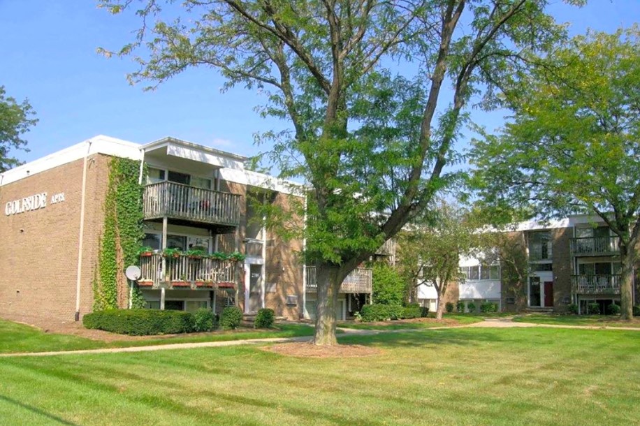 an exterior view of an apartment building with grass and trees